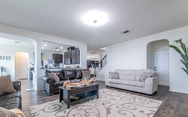living room featuring arched walkways, wood finished floors, stairs, and recessed lighting