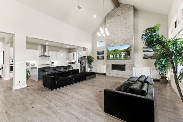 321 Cumberland Cv, Georgetown, TX 78628 - living room featuring high vaulted ceiling, a chandelier, beam ceiling, light wood-style floors, and a fireplace