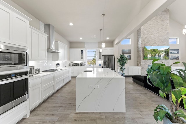 321 Cumberland Cv, Georgetown, TX 78628 - kitchen featuring stainless steel appliances, wall chimney exhaust hood, a sink, a kitchen island with sink, and decorative backsplash