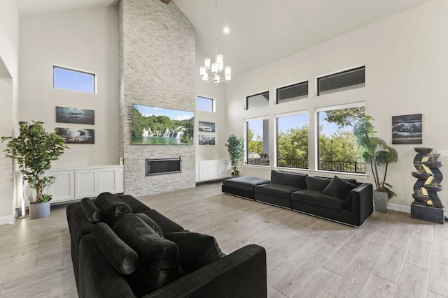 321 Cumberland Cv, Georgetown, TX 78628 - living area featuring high vaulted ceiling, a chandelier, wood finished floors, a stone fireplace, and baseboards