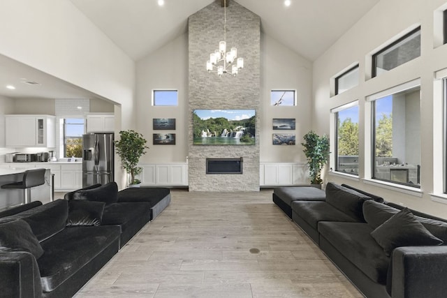 321 Cumberland Cv, Georgetown, TX 78628 - living room with high vaulted ceiling, light wood-type flooring, wainscoting, a chandelier, and a fireplace