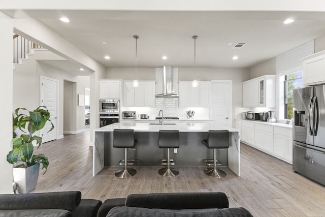 321 Cumberland Cv, Georgetown, TX 78628 - kitchen with stainless steel appliances, wall chimney exhaust hood, a breakfast bar, decorative backsplash, and recessed lighting