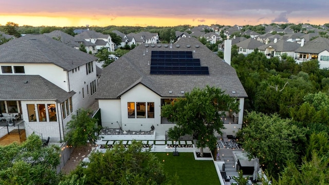 321 Cumberland Cv, Georgetown, TX 78628 - back of house featuring a residential view, roof mounted solar panels, a shingled roof, and stucco siding