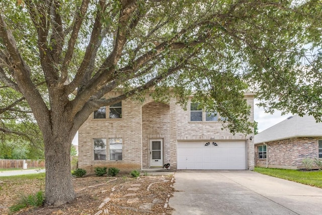 view of front of house with an attached garage, driveway, brick siding, and fence