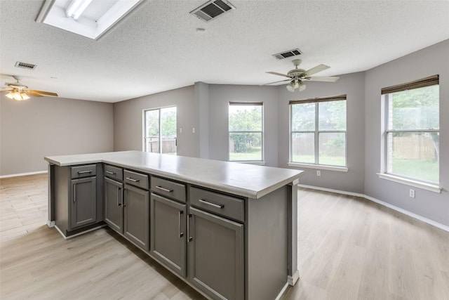 kitchen with a ceiling fan, gray cabinetry, open floor plan, and a textured ceiling