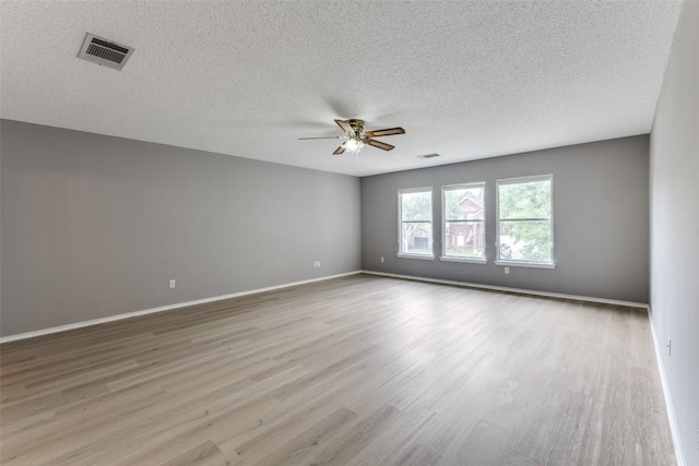 empty room with a ceiling fan, wood finished floors, a textured ceiling, and baseboards