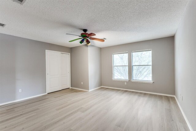 empty room with wood finished floors, ceiling fan, a textured ceiling, and baseboards