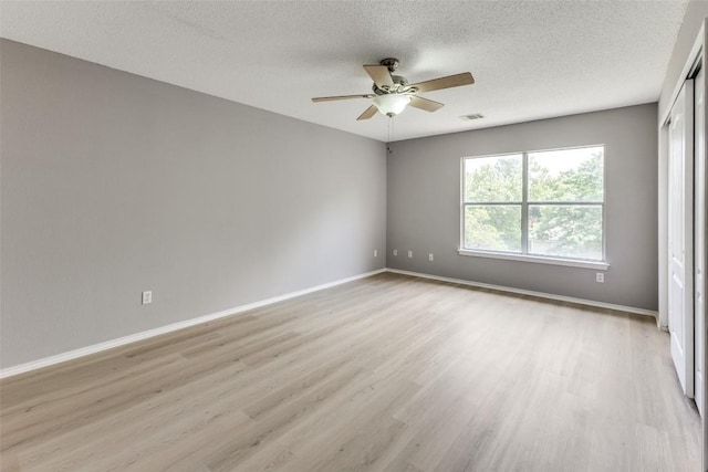unfurnished room with light wood-style floors, ceiling fan, baseboards, and a textured ceiling