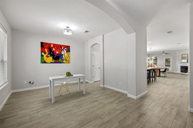 dining space with arched walkways, light wood-style floors, plenty of natural light, and baseboards