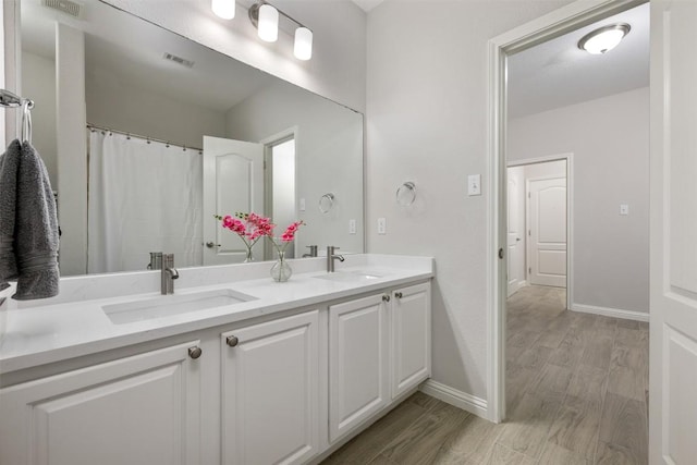 full bathroom featuring double vanity, baseboards, and wood finished floors