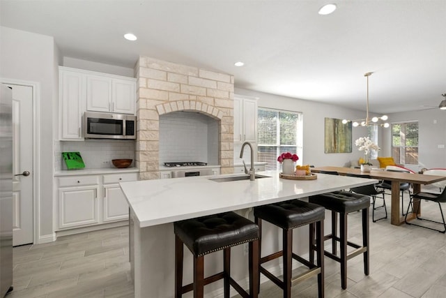 kitchen with a sink, stainless steel microwave, decorative backsplash, plenty of natural light, and recessed lighting