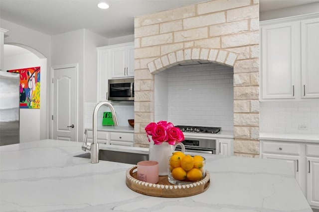 kitchen with appliances with stainless steel finishes, white cabinets, tasteful backsplash, and recessed lighting
