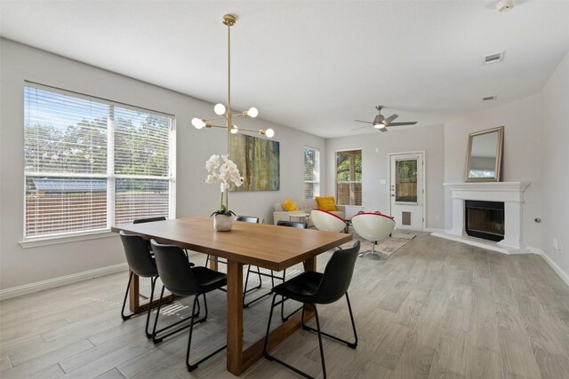 dining room with healthy amount of natural light, light wood-style flooring, and baseboards