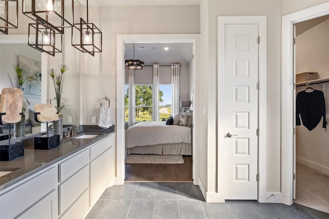 217 Northcrest Dr, Liberty Hill, TX 78642 - bathroom with a chandelier, double vanity, baseboards, connected bathroom, and a spacious closet