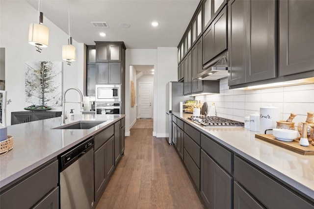 217 Northcrest Dr, Liberty Hill, TX 78642 - kitchen featuring stainless steel appliances, a sink, under cabinet range hood, backsplash, and wood finished floors