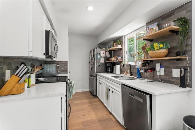 2312 Aldford Dr, Austin, TX 78745 - kitchen featuring stainless steel appliances, open shelves, a sink, light wood finished floors, and white cabinets
