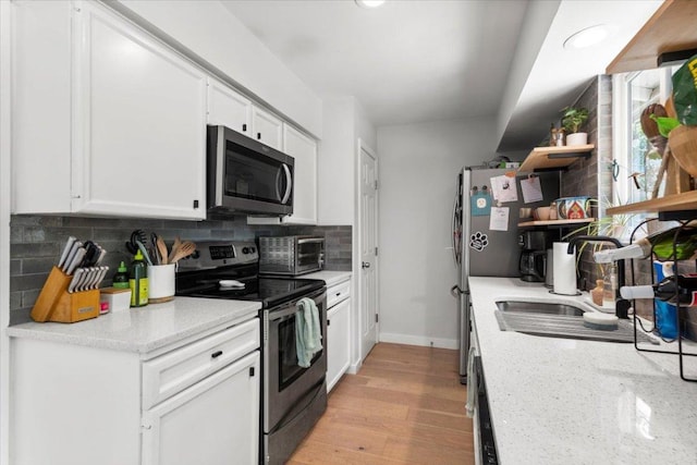 2312 Aldford Dr, Austin, TX 78745 - kitchen with appliances with stainless steel finishes, open shelves, backsplash, white cabinetry, and light wood-type flooring