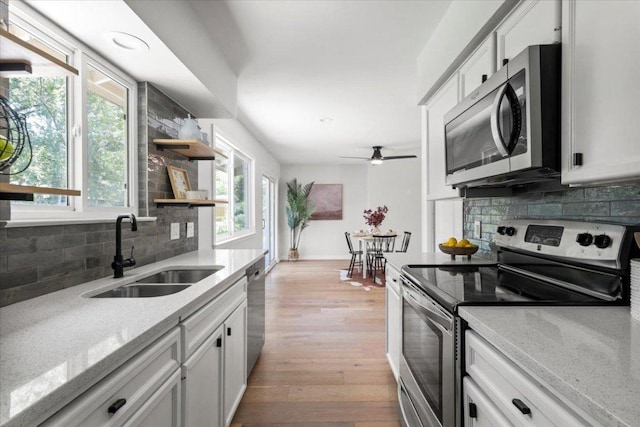 2312 Aldford Dr, Austin, TX 78745 - kitchen with stainless steel appliances, decorative backsplash, open shelves, light wood-type flooring, and a ceiling fan
