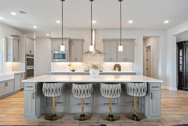 513 Red Yucca Ct, Liberty Hill, TX 78642 - kitchen featuring gray cabinets, wall chimney exhaust hood, stainless steel appliances, a spacious island, and tasteful backsplash