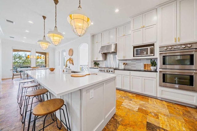 3500 River Oaks Dr, Kingsland, TX 78639 - kitchen featuring stainless steel appliances, stone tile floors, under cabinet range hood, recessed lighting, and decorative backsplash