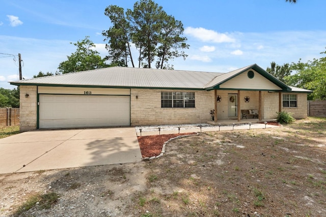 single story home with a garage, driveway, metal roof, covered porch, and fence