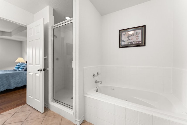 ensuite bathroom featuring a shower stall, a garden tub, and tile patterned floors