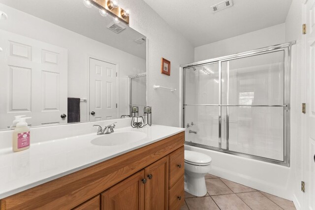 bathroom with tile patterned floors, toilet, vanity, and enclosed tub / shower combo