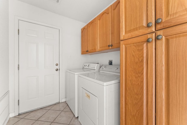 washroom featuring washer and clothes dryer, cabinet space, and light tile patterned flooring