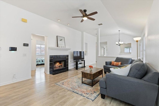21223 Byerly Turk Dr, Pflugerville, TX 78660 - living room featuring a chandelier, a ceiling fan, vaulted ceiling, a fireplace, and light wood-type flooring