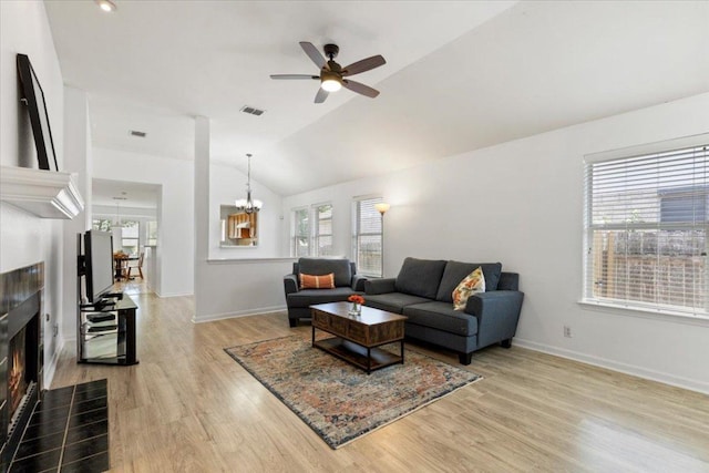 21223 Byerly Turk Dr, Pflugerville, TX 78660 - living room featuring a fireplace, a chandelier, a ceiling fan, lofted ceiling, and light wood-style flooring