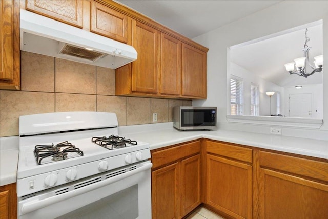 21223 Byerly Turk Dr, Pflugerville, TX 78660 - kitchen featuring white gas range oven, under cabinet range hood, stainless steel microwave, brown cabinetry, and a chandelier