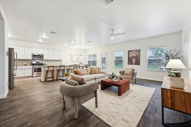 living area with dark wood-style flooring, ceiling fan, baseboards, and a chandelier