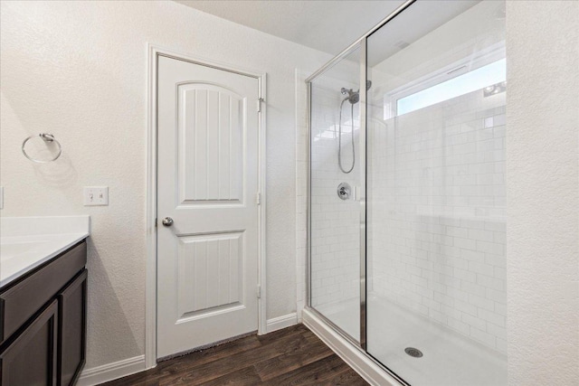 bathroom featuring a stall shower, wood finished floors, vanity, and baseboards