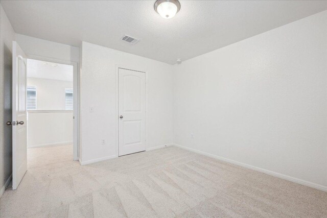 unfurnished bedroom featuring light carpet and baseboards