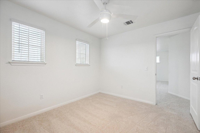 carpeted empty room with ceiling fan and baseboards