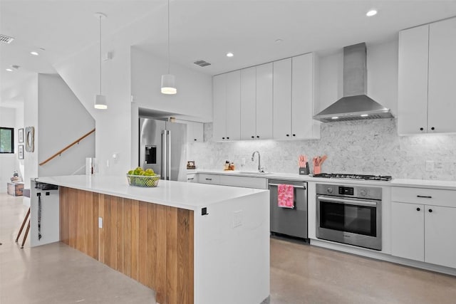 kitchen featuring stainless steel appliances, wall chimney range hood, decorative backsplash, a sink, and recessed lighting