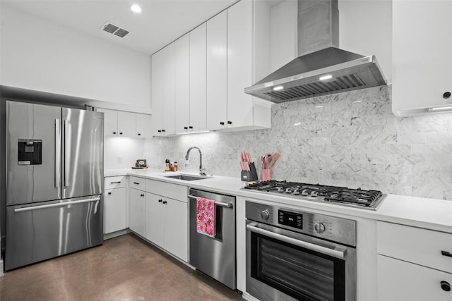 kitchen featuring stainless steel appliances, wall chimney range hood, a sink, light countertops, and white cabinetry