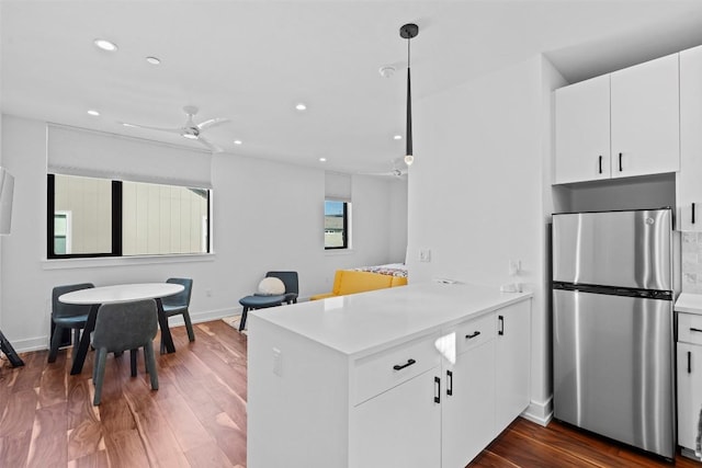 kitchen featuring freestanding refrigerator, a peninsula, light countertops, white cabinetry, and baseboards
