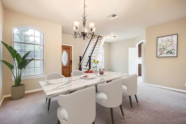 dining space featuring light carpet, stairway, a chandelier, and baseboards