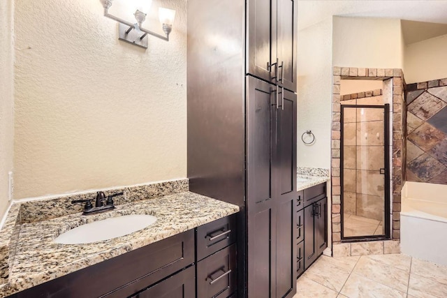 bathroom with a shower stall, vanity, a bath, and a textured wall