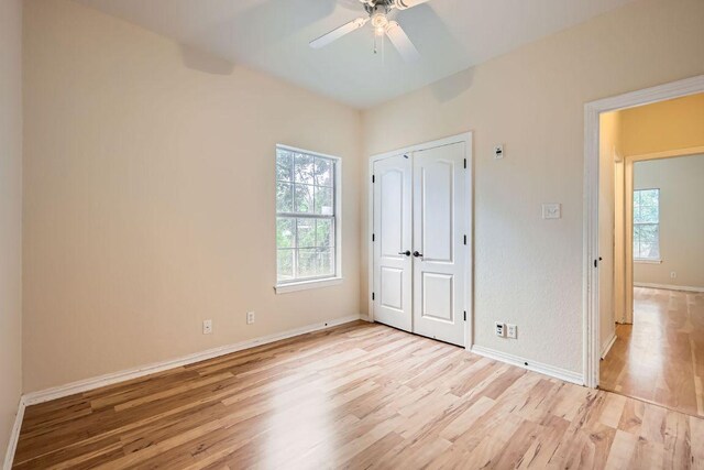 unfurnished bedroom with light wood-type flooring, baseboards, a ceiling fan, and a closet
