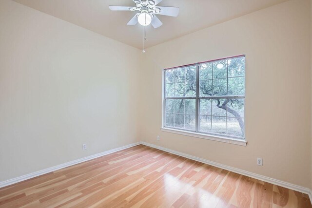 spare room with baseboards, light wood finished floors, and ceiling fan