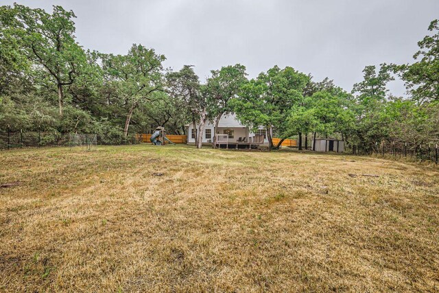 view of yard featuring a shed, a playground, an outbuilding, and a wooden deck