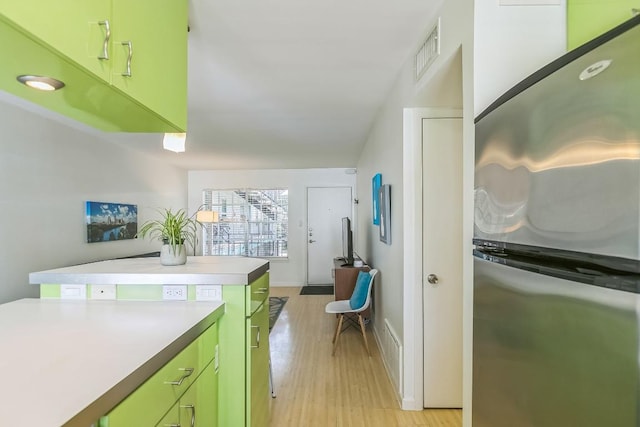 300 Crockett St Unit 210, Austin, TX 78704 - kitchen with freestanding refrigerator, green cabinetry, light wood finished floors, light countertops, and baseboards