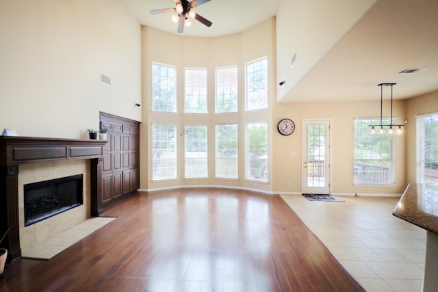 2702 Quiet Moon Trl, Cedar Park, TX 78613 - unfurnished living room with ceiling fan, a tiled fireplace, a high ceiling, and wood finished floors