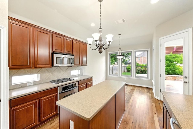 kitchen with appliances with stainless steel finishes, a chandelier, plenty of natural light, and decorative backsplash