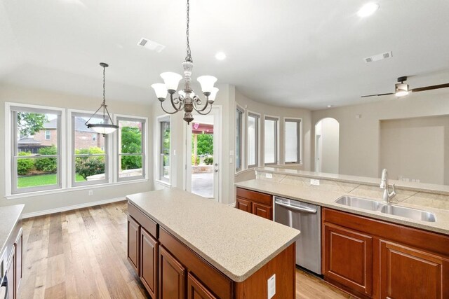 kitchen with a sink, dishwasher, arched walkways, and light countertops