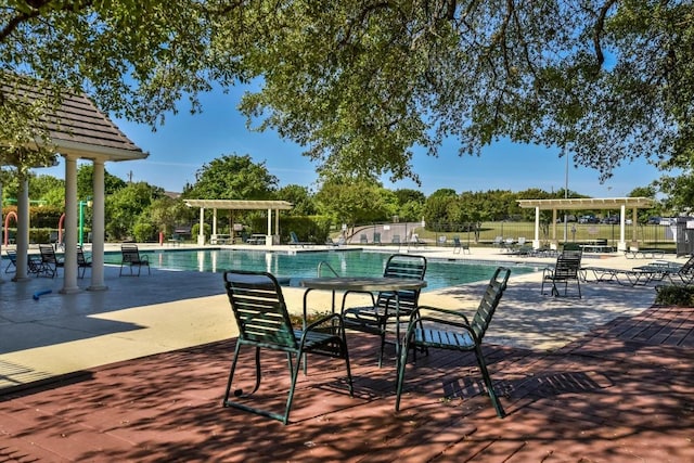 community pool with a pergola, fence, and a patio