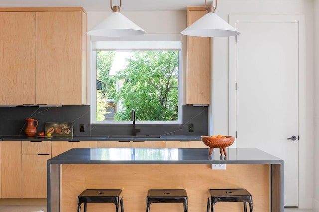 2305 E 17th St Unit B, Austin, TX 78702 - kitchen with light brown cabinetry, dark countertops, a breakfast bar area, a sink, and decorative backsplash