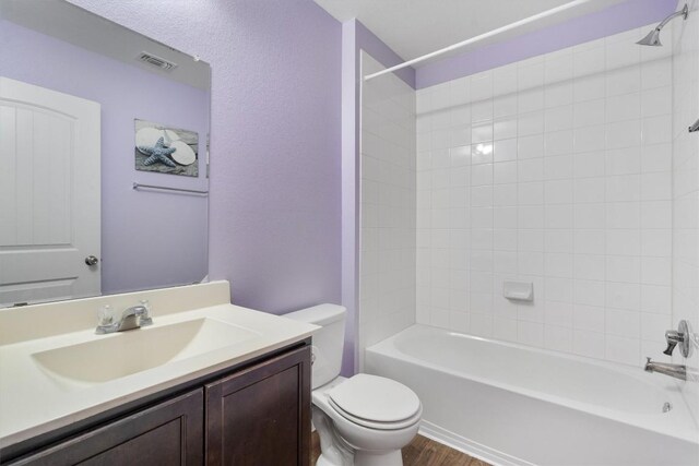 bathroom featuring toilet, vanity, wood finished floors, and  shower combination